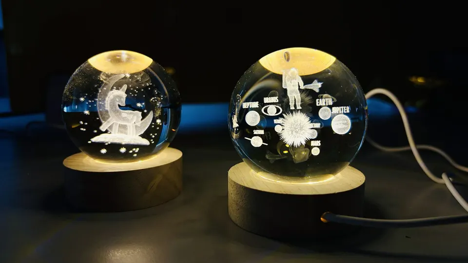Two laser-engraved crystal balls on lit wooden bases