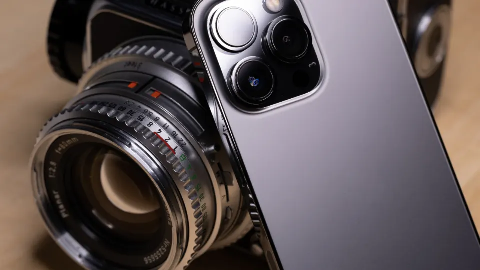 Smartphone beside a vintage camera lens