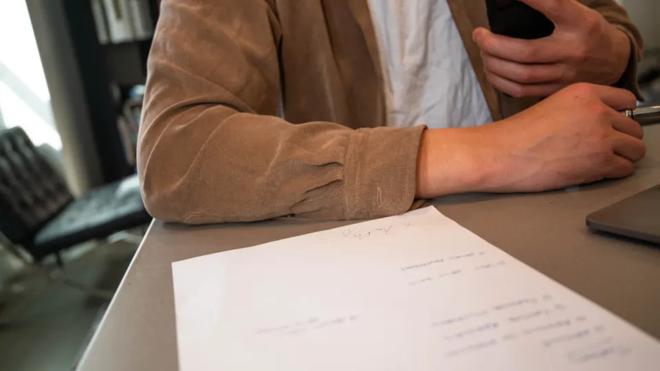 Person signing a paper document at a desk